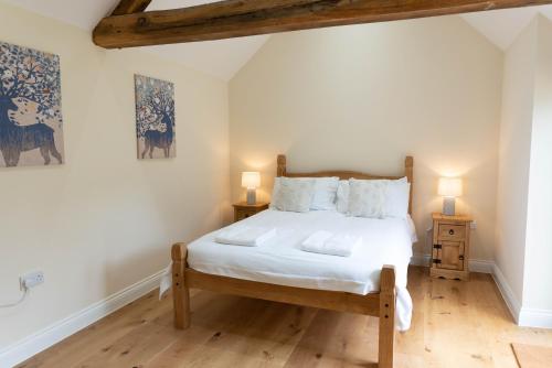 a bedroom with a bed with white sheets and two lamps at Lovely 1-bed suite & bathroom in converted barn near Newark Show-Ground 
