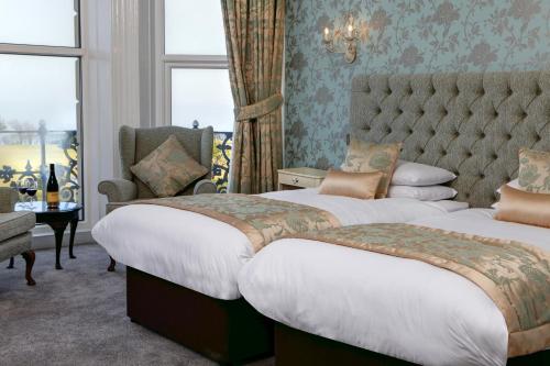 a hotel room with two beds and a chair at The Lansdowne, Eastbourne in Eastbourne