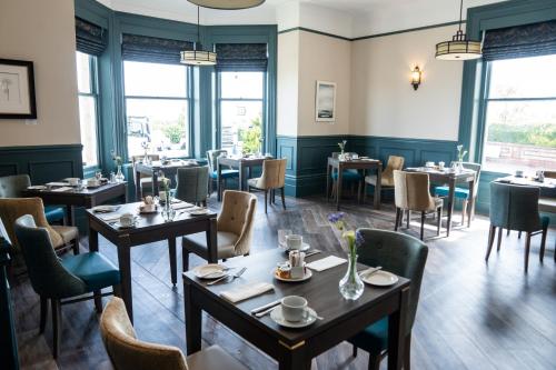 a restaurant with tables and chairs and windows at The Lansdowne, Eastbourne in Eastbourne