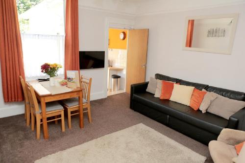 a living room with a black couch and a table at Abbey View Holiday Flats in Torquay