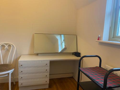 a bedroom with a desk with a mirror and a chair at Cotswolds house in Cirencester