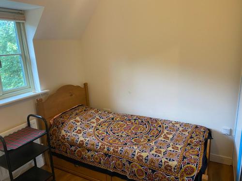 a small bedroom with a bed with a patterned blanket at Cotswolds house in Cirencester