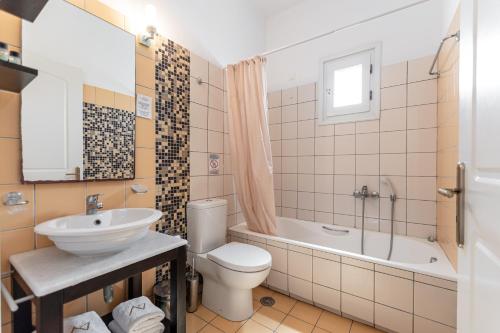 a bathroom with a toilet and a sink and a tub at Annita's Village Hotel in Agia Anna Naxos