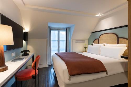 um quarto de hotel com uma cama, uma secretária e uma cadeira em The Chess Hotel em Paris