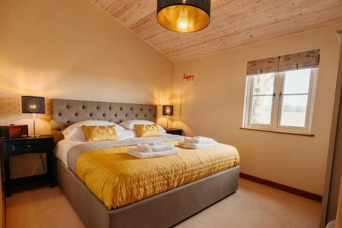 um quarto com uma cama grande com lençóis amarelos e uma janela em Beautiful Cottage in Bredfield near to Woodbridge on the Suffolk Coast em Bredfield