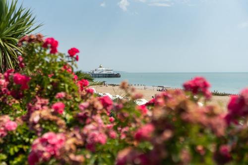 a beach with pink flowers and a cruise ship in the water at The Lansdowne, Eastbourne in Eastbourne