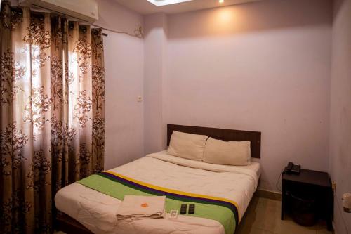 a small bedroom with a bed and curtains at Hotel City View INN in Guwahati