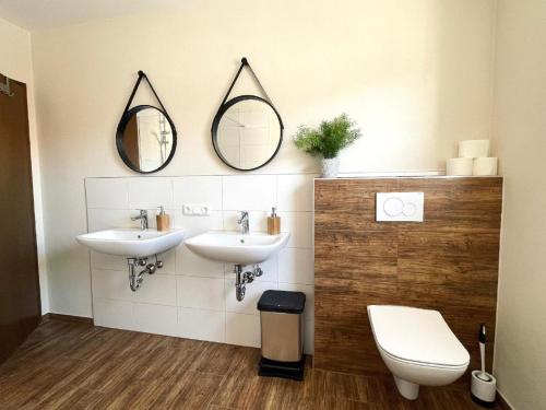 uma casa de banho com 2 lavatórios e um WC e espelhos em Ferienwohnung Hoamatgfühl em Furth im Wald