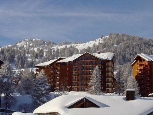 een hotel in de sneeuw met een berg op de achtergrond bij RISOUL - Résidence ALTAIR - 5 couchages - À 1min à pieds des pistes in Risoul