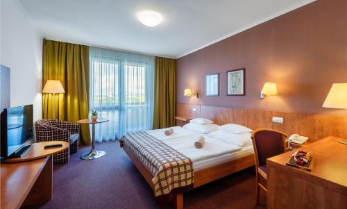 タポルツァにあるHunguest Hotel Pelionのベッドとデスクが備わるホテルルームです。