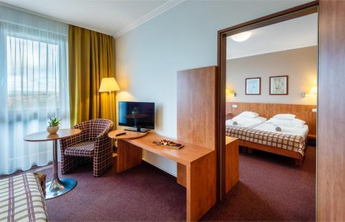 a hotel room with a bed and a desk with a television at Hunguest Hotel Pelion in Tapolca