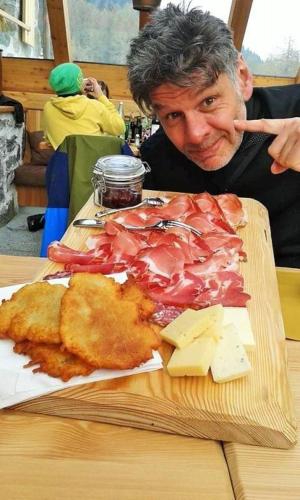 a man sitting at a table with a plate of food at Brici's House 69 in Passo del Tonale