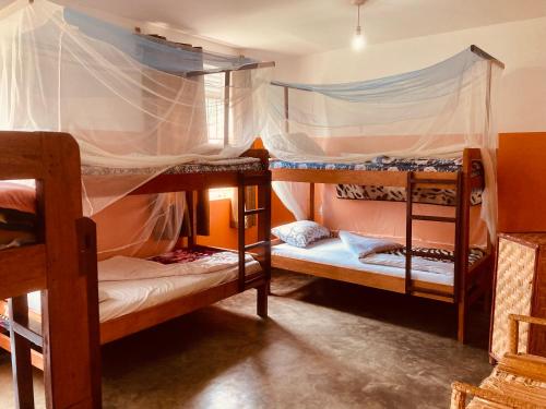 a bedroom with two bunk beds with mosquito nets at Yes Hostel in Fort Portal