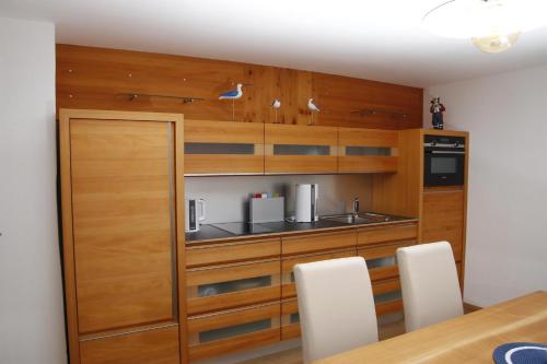 a kitchen with wooden cabinets and a table and chairs at Ferienwohnung Loretta in Hergatz