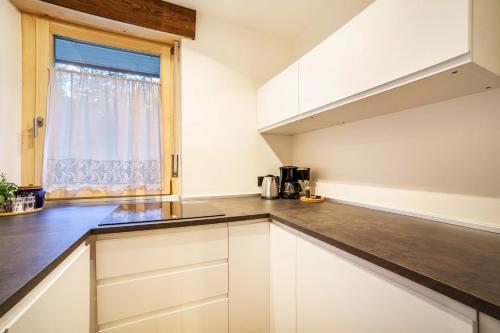 a kitchen with white cabinets and a window at Ferienwohnung Kuppelwies 363 in Ultimo