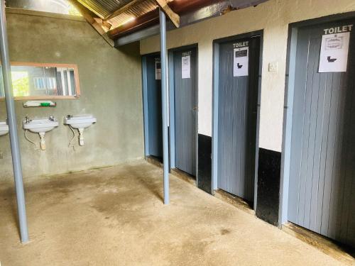 uma casa de banho com três urinóis e três lavatórios em Yes Hostel em Fort Portal