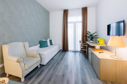 Habitación con sofá, silla y escritorio. en Hotel Mioni Royal San, en Montegrotto Terme