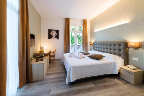 a hotel room with a bed and a desk and a window at Hotel Mioni Royal San in Montegrotto Terme