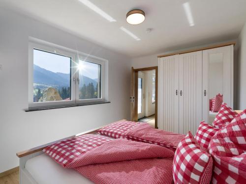 1 dormitorio con almohadas rojas y blancas y ventana en Apartment Heimatliebe, en Scheffau am Wilden Kaiser