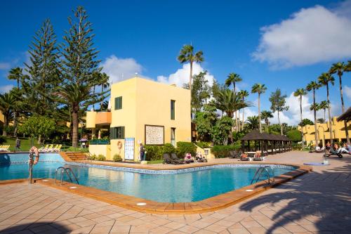 une piscine dans un complexe hôtelier avec des palmiers et un bâtiment dans l'établissement Oeste Tere by Best Holidays Fuerteventura, à Corralejo