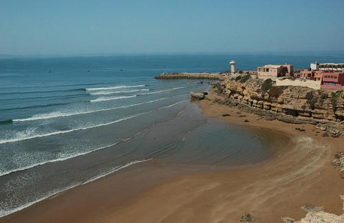 una vista aerea di una spiaggia con un faro di House Tayought Imsouane a Imsouane