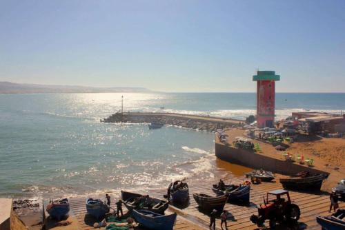 een groep boten op een strand met een vuurtoren bij House Tayought Imsouane in Imsouane