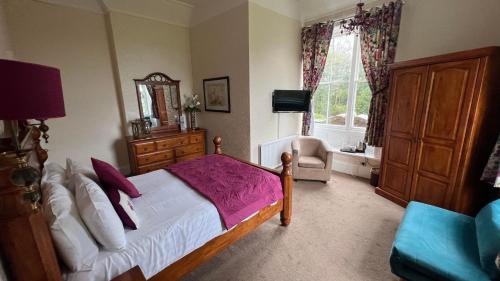 a bedroom with a bed and a chair and a window at Broughton Craggs Hotel in Cockermouth