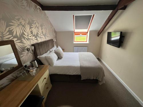 a small bedroom with a bed and a mirror at Broughton Craggs Hotel in Cockermouth