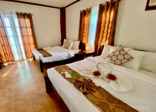 a bedroom with two beds and a room with windows at Sophias Beach Guest House in El Nido