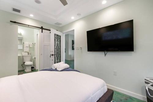 Schlafzimmer mit einem großen weißen Bett und einem Flachbild-TV in der Unterkunft Heated Pool I Soundproof Home I Firepit I 630Mbps in Hollywood