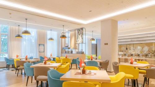 a restaurant with yellow and blue chairs and tables at Holiday Inn Shanghai Dishui Lake by IHG in Nanhui