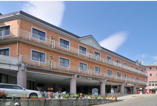 a large brick building with a car parked in front of it at Hotel Sunplaza Tsugaike in Otari