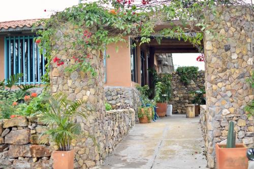 an entrance to a stone wall with flowers and plants at Cabaña en la Mesa de los Santos in Pescadero