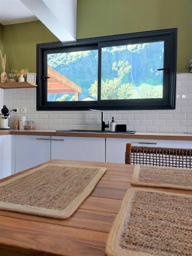 a kitchen with a table with a large window at Villa Couleur Nature in Salazie