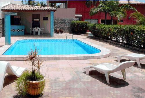 a swimming pool with two chairs and a table at Pousada Abais in Aracaju