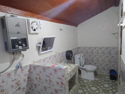 a bathroom with a toilet and a tv on the wall at Lung Soi Nguen Homstay Pang Oung in Pang Ung