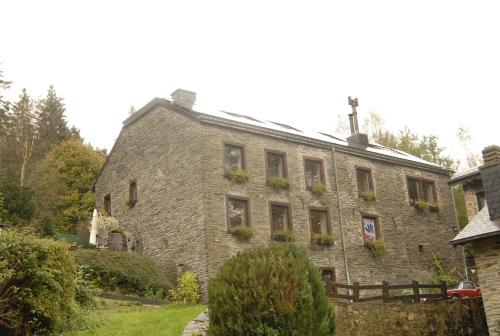 an old stone building with flowers on the windows at Le Clos Arboré (Gîte) in Libramont