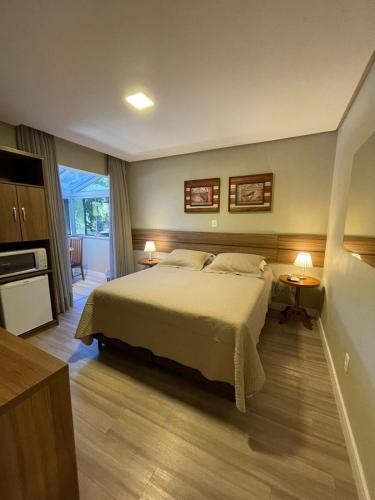 a bedroom with a large bed and a kitchen at Residencial Jardim dos Pinheiros B in Canela