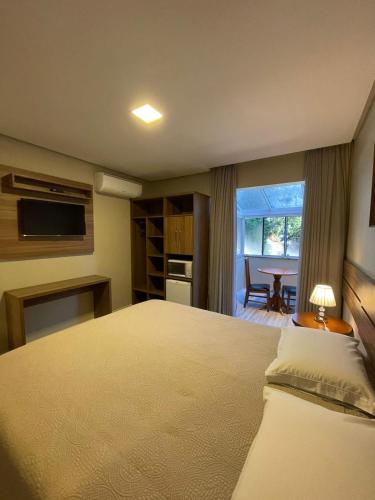 a bedroom with a bed and a table and a window at Residencial Jardim dos Pinheiros B in Canela