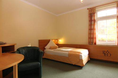 a bedroom with a bed and a chair and a table at Rabenauer Mühle "bed & breakfast" in Rabenau