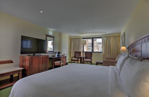 a hotel room with a large bed and a desk at Dominican Fiesta Hotel in Santo Domingo