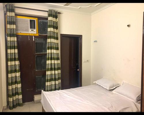 a bedroom with a bed and a window with a microwave at Malik Guest House By WB Inn in Gurgaon