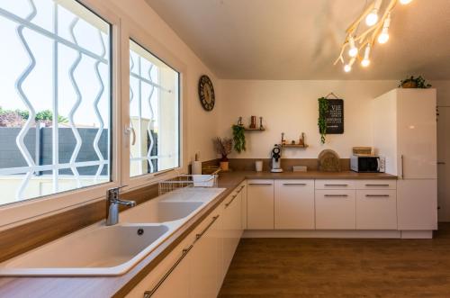 a kitchen with a sink and a large window at Villa des Oliviers : Sublime villa avec piscine chauffée et privée, terrasse de 185m² in Bon-Encontre