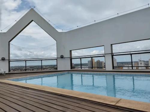 a swimming pool on the roof of a building with windows at Apto acolhedor, confortável e bem localizado in Campos dos Goytacazes