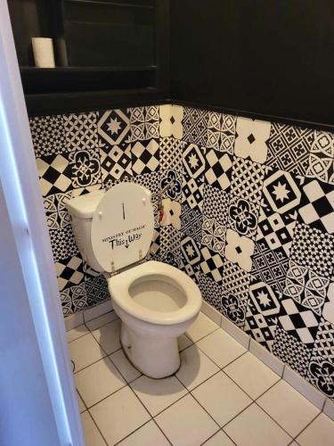 a bathroom with a toilet with black and white tiles at Appartement spacieux Asnièresa in Asnières-sur-Seine