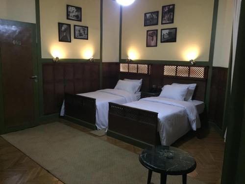 a bedroom with two beds and a table and pictures on the wall at Carlton Downtown Cairo in Cairo