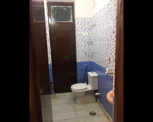 a bathroom with a toilet and a blue wall at Malik Guest House By WB Inn in Gurgaon