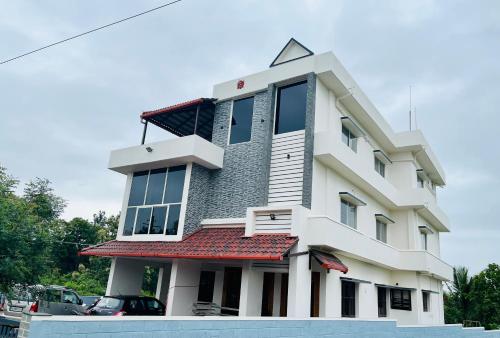 a large white building with a red roof at Darshan Arrive & Revive Homestay. in Kushālnagar