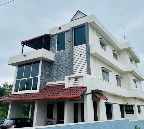 um edifício branco com um telhado vermelho em Darshan Arrive & Revive Homestay. em Kushalanagar