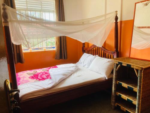a bed with a canopy in a room with a window at Yes Hostel in Fort Portal